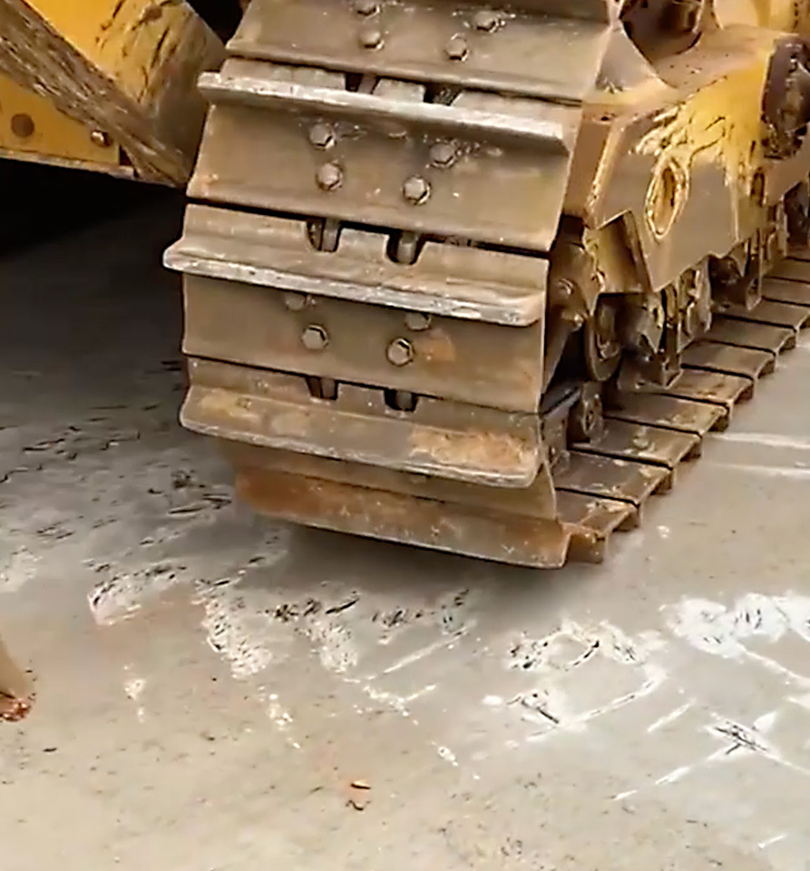 Heavy construction machinery track on a MEGASLAB concrete surface, showcasing durability.