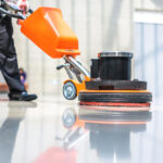 Person maintaining an industrial concrete floor with a cleaning machine