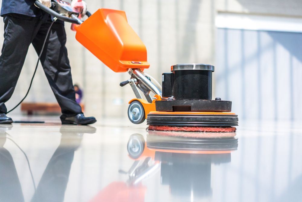 Person maintaining an industrial concrete floor with a cleaning machine